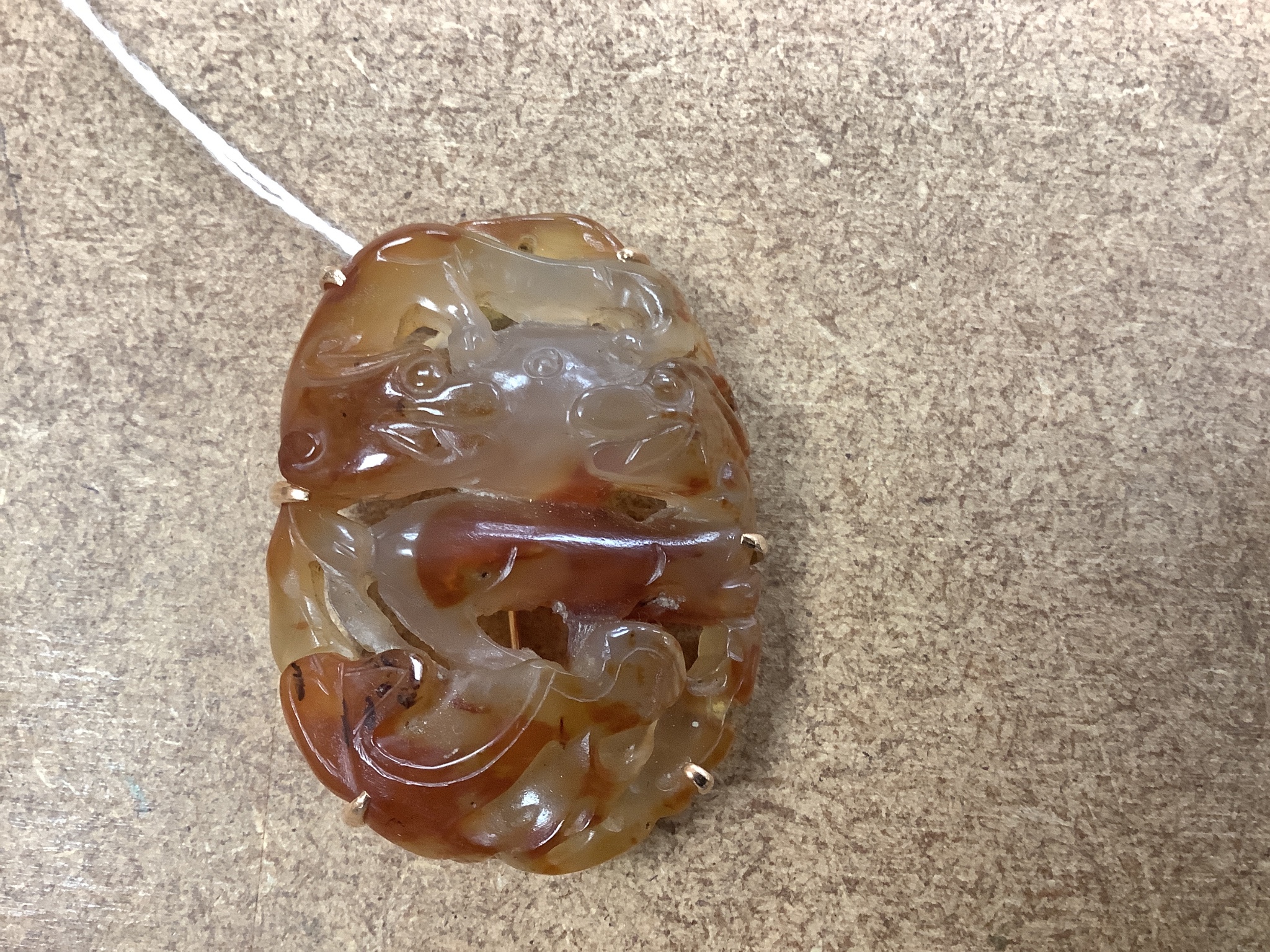 A Chinese carved agate plaque, Qing dynasty, later mounted as a brooch, 5.5cm long